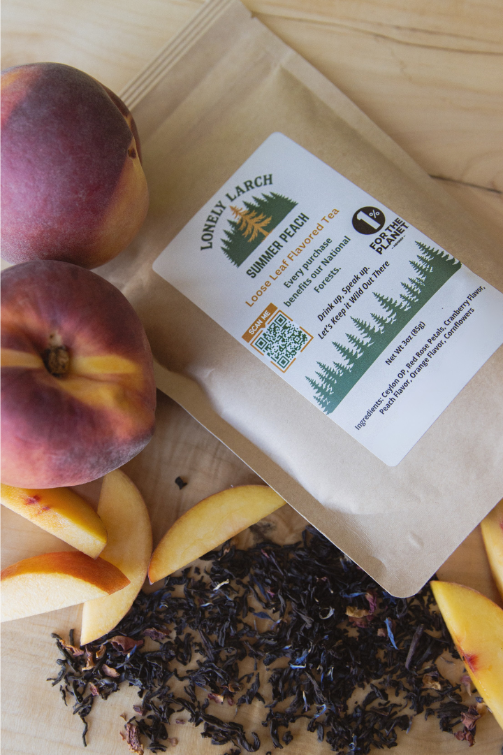 Tea package with a label on a wooden surface with peaches and tea leaves.