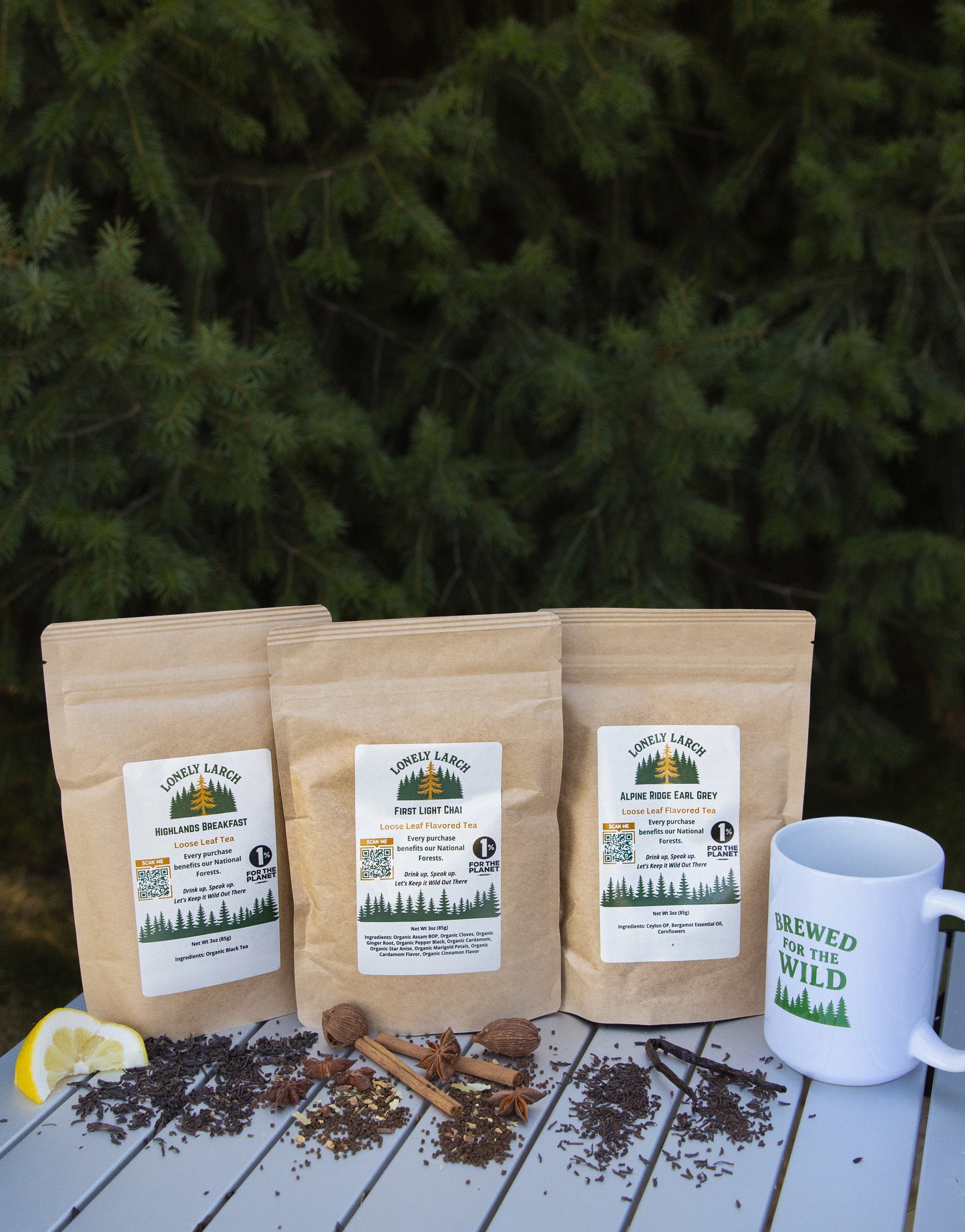 Three brown paper bags with labels and a white mug on a wooden surface with a greenery background