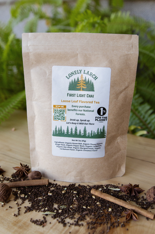 Tea package with a label on a wooden surface with tea leaves and cinnamon sticks.